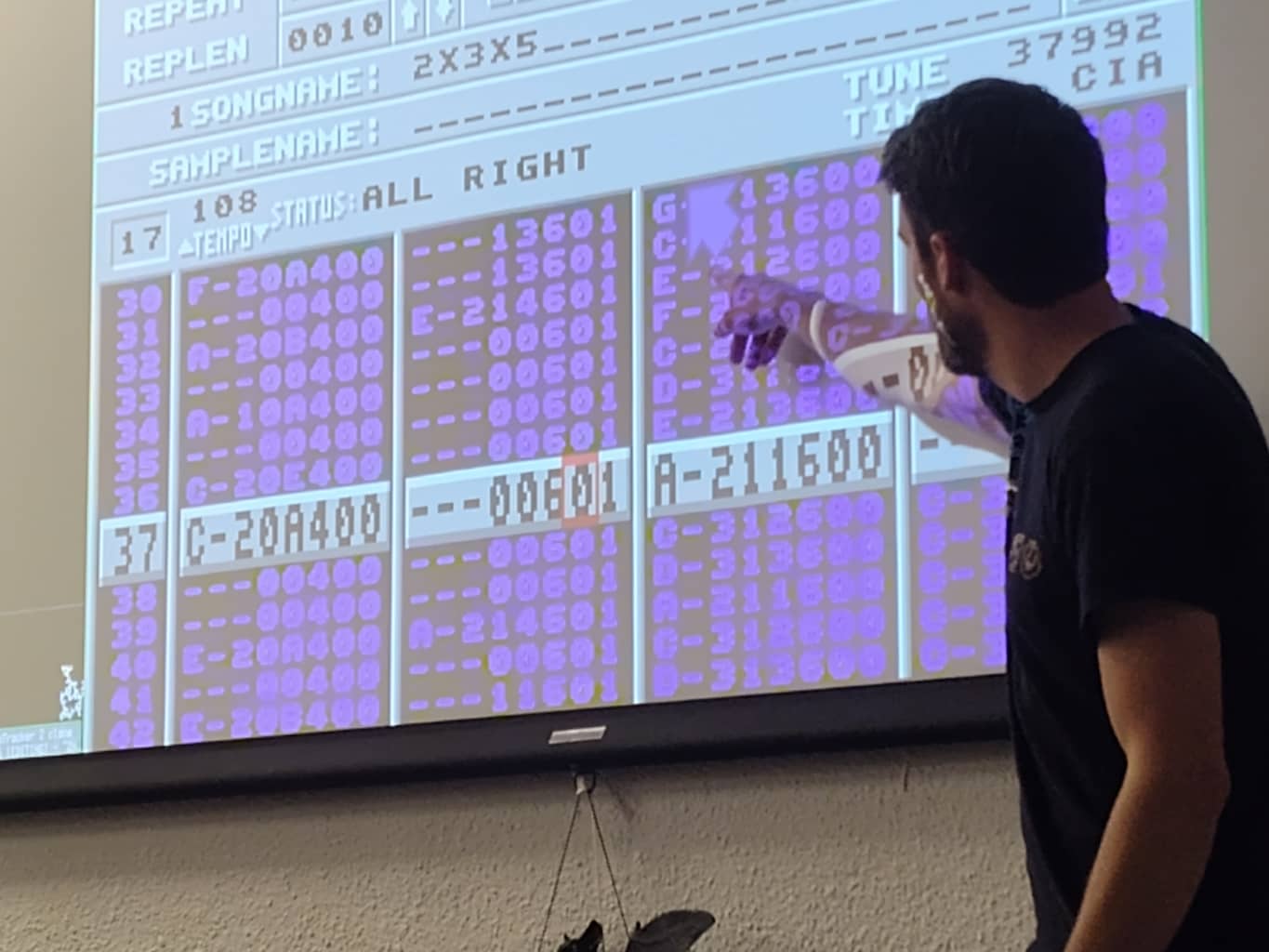 presenter pointing at a tracker software interface projected on a large screen