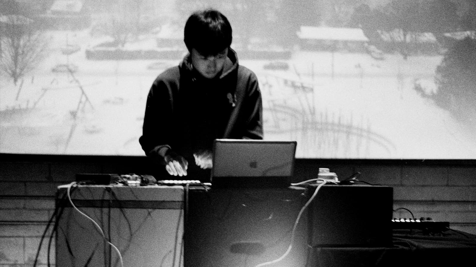 artist performing live with a laptop and MIDI controller, black and white photo