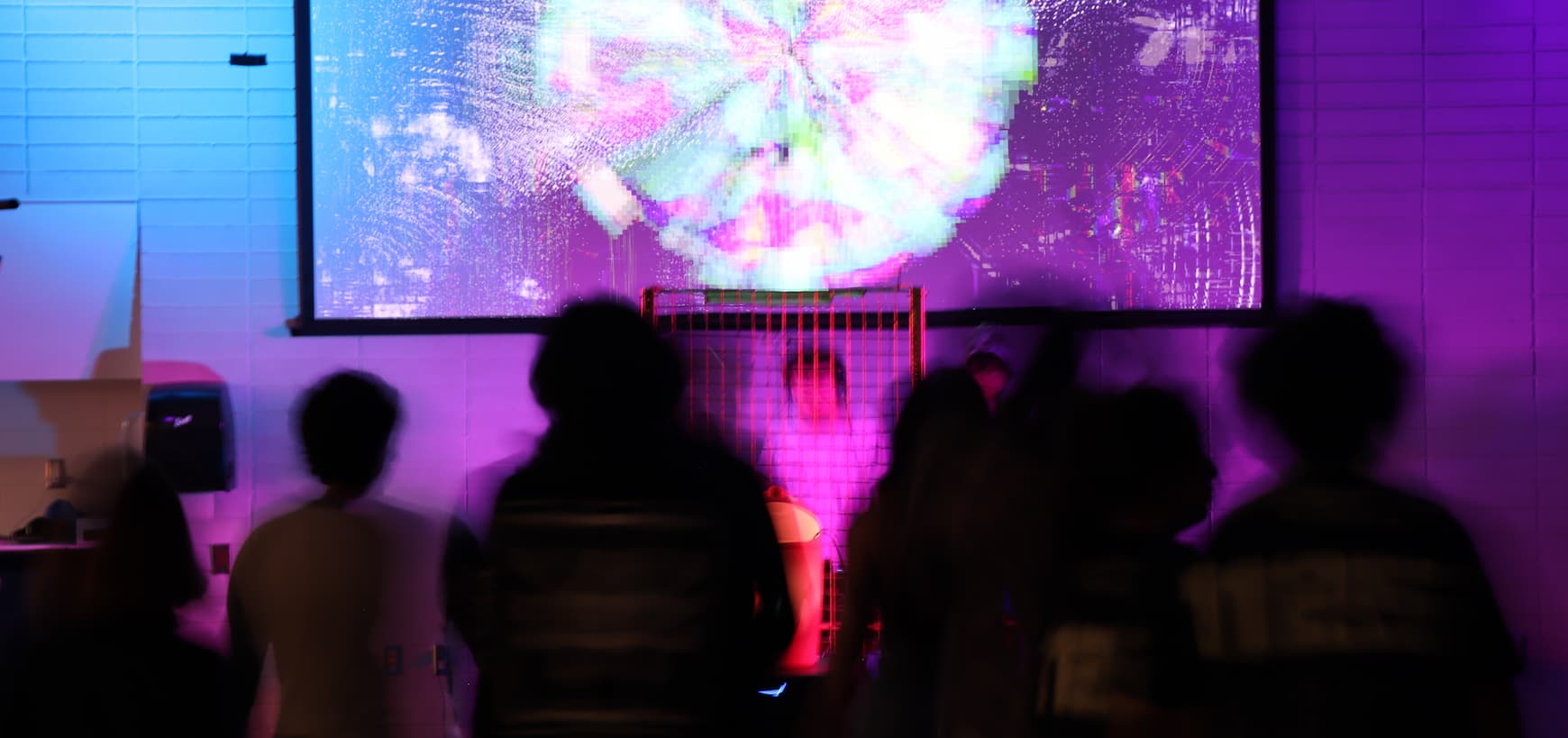 audience watching a live AV performance, colourful glitch visuals projected on screen